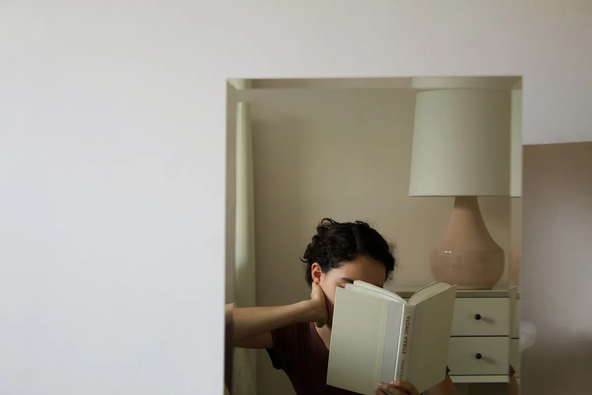 frau liest buch vor einem spiegel